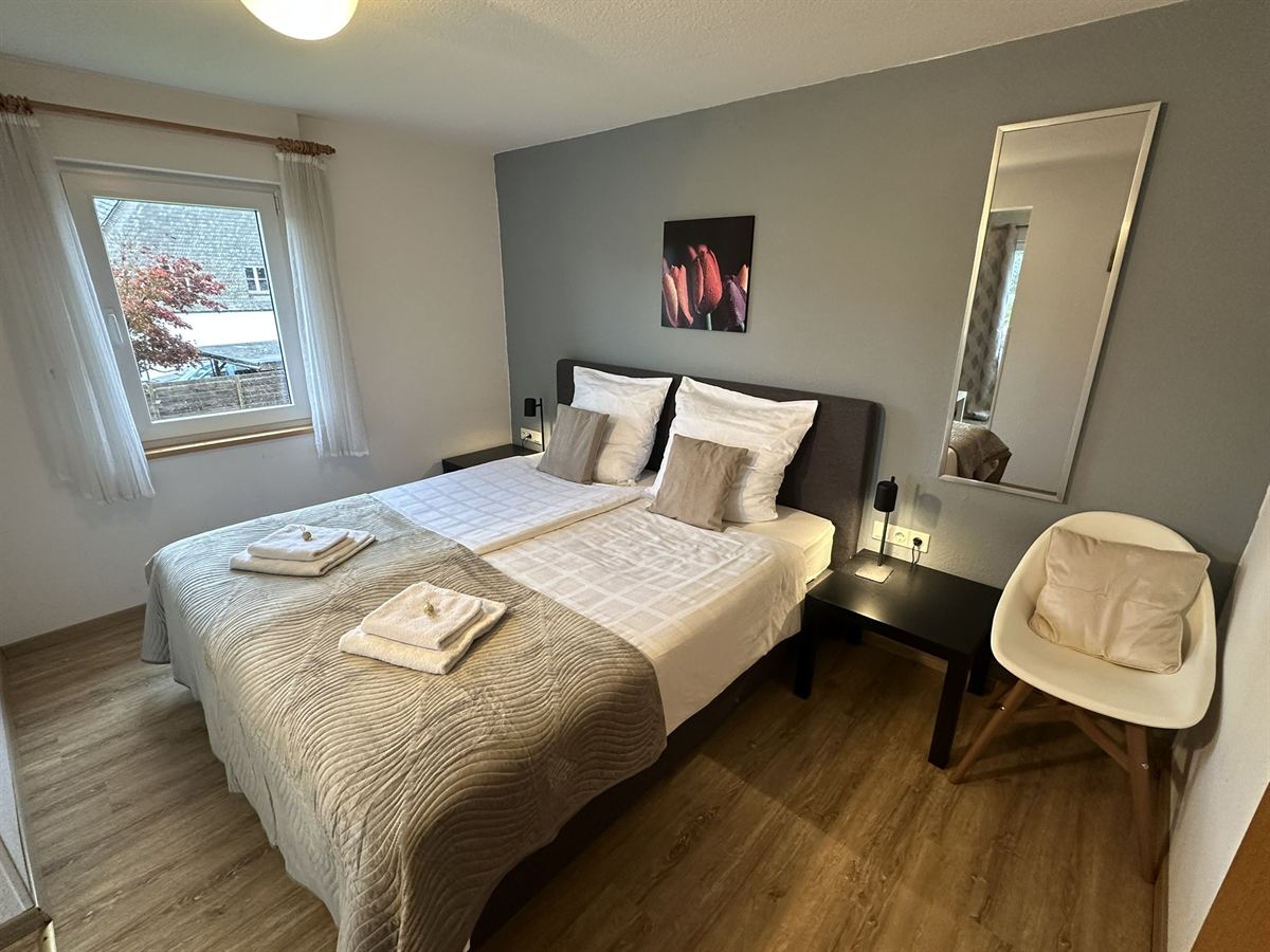 Helles Zimmer mit Boxspringbett und Balkon in der Pension Haus Astenalm
